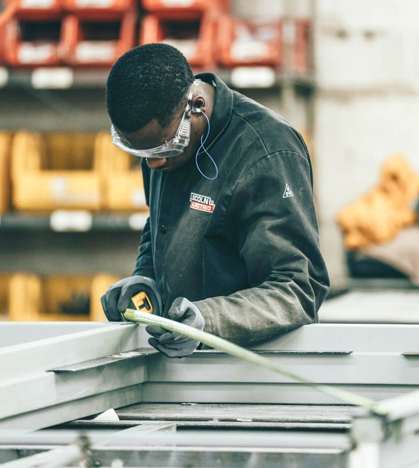 Man Using Measuring Tape in Factory Setting